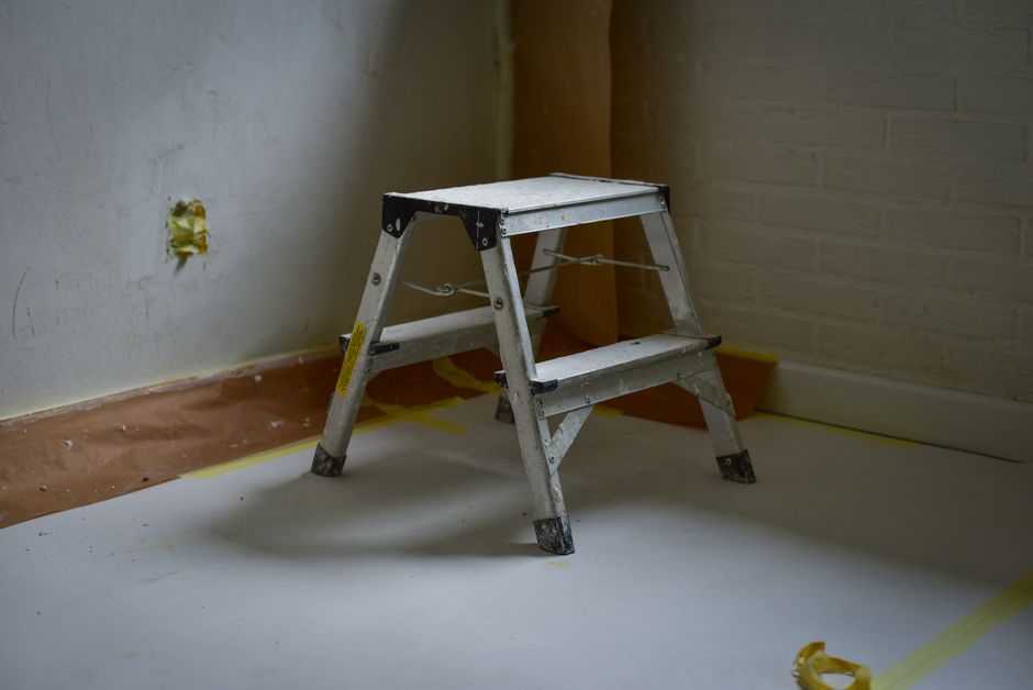 Een vakman repareert een cementdekvloer met gereedschap en materialen voor een gladde afwerking.